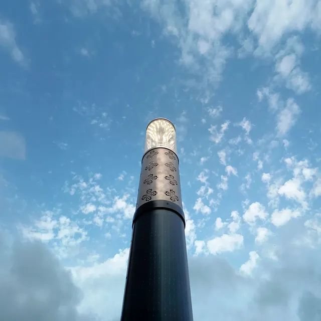 Coluna de iluminação BBYey vista de baixo contra o céu azul com nuvens